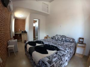 1 dormitorio con cama y pared de ladrillo en Paul's kitchenettes da praia & Nemo dive, centro de mergulho, en Santa Cruz Cabrália