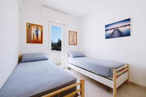two twin beds in a room with a window at Casa Boarni Leuca in Leuca