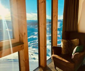 um quarto com uma cadeira e uma janela com neve em Lodge am Krippenstein em Obertraun