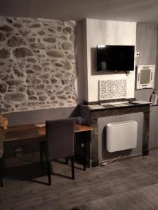 Pokój z biurkiem, telewizorem i ścianą w obiekcie Maison de ville au pied de la Montagne Noire w mieście Mazamet