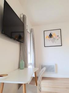 a living room with a white table and a television on a wall at Studio hyper centre avec balcon in Châteauroux