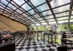 un restaurante con techo de cristal, mesas y sillas en Estanplaza Funchal Faria Lima, en São Paulo