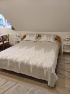 a bedroom with a large white bed with two pillows at Gólya Vendégház in Tiszaug