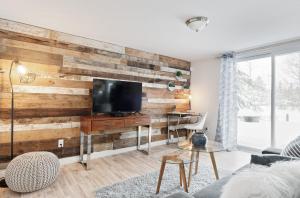 a living room with a wooden wall with a tv at Chez Elisabeth et Andrew in Saint-Raymond