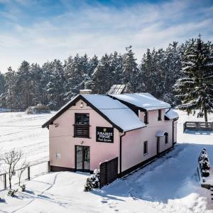 a pink house in the snow with trees at Jurajskie Pokoje Pod Lasem in Żarki