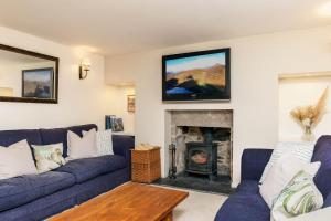 Una sala de estar con un sofá azul y una chimenea. en Riverside Cottage with wood fired hot tub in Cairngorms, en Ballater