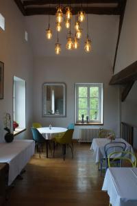 Le Moulin 1826 في Houdan: غرفة طعام مع طاولات وكراسي وأضواء