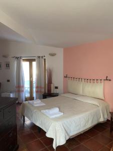 a bedroom with a large bed with two towels on it at Locanda Tipica Sa Corte in Oliena