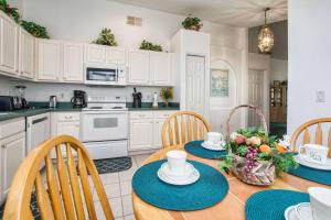 una cocina con mesa y sillas y una cocina con armarios blancos. en Indian Ridge - 4 Bedroom Pool Home- 2408IR, en Orlando