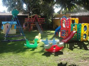 un parque infantil con diferentes tipos de juguetes en la hierba en Casa aconchego Geribá canto direito 2Q com WiFi, en Búzios