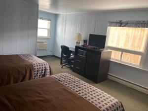 a hotel room with two beds and a desk and a television at All Seasons Motel in Port Elgin