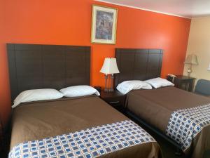 two beds in a hotel room with orange walls at All Seasons Motel in Port Elgin