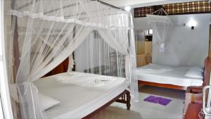 two beds in a room with white mosquito nets at Sea view Beach Resort in Unawatuna