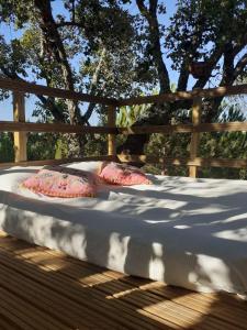 a bed with two pillows sitting on a wooden deck at Quinta Alada in Montemor-o-Novo