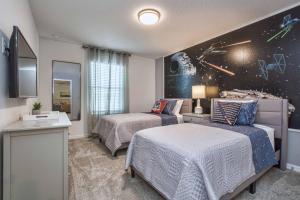 1 dormitorio con 2 camas y una pared temática espacial en 5 Bedrooms Townhome w- Splashpool - 8205SA, en Orlando