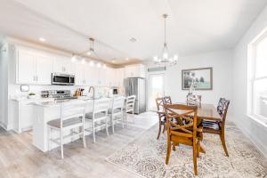 a kitchen with white cabinets and a table and chairs at Latitude Adjustment in Dauphin Island