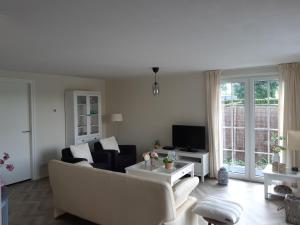 een witte woonkamer met een bank en een tv bij Nieuwe Beachbungalow aan IJsselmeer 39 24 four seasons in Lemmer