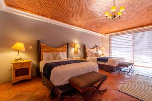 een slaapkamer met 2 bedden en een kroonluchter bij Hotel Camino de Vinos in Guanajuato