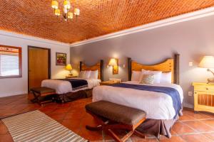 een hotelkamer met 2 bedden en 2 stoelen bij Hotel Camino de Vinos in Guanajuato