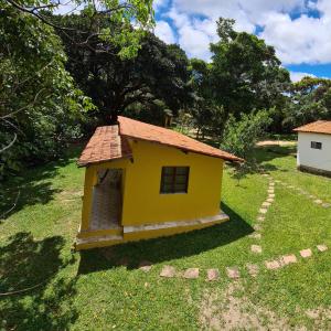 a small yellow house in the middle of a yard at Casa da Trilha in Vale do Capao