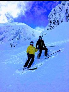 Due persone stanno sciando giù da una montagna innevata di Tower Ridge House a Fort William