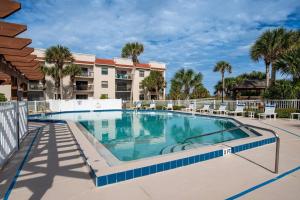 a swimming pool at a resort with chairs and a building at Driftwood Escape in Saint Augustine Beach