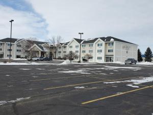 an empty parking lot with a large apartment complex at Cobblestone Suites - Oshkosh in Oshkosh