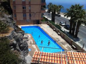a swimming pool with people in it next to the ocean at Marina Habanera in Almuñécar