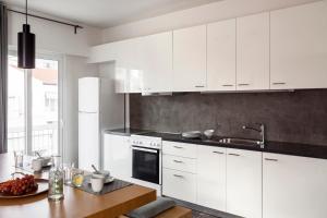 a kitchen with white cabinets and a wooden table at Sea View Beach Penthouse - Athens Coast in Athens