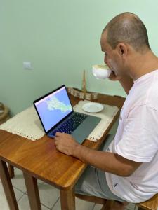un hombre sentado en una mesa con un ordenador portátil en La Estancia Ideal Apartamentos en Fortuna
