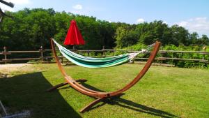 a hammock with a red umbrella on the grass at Retour Au Source in Monprimblanc