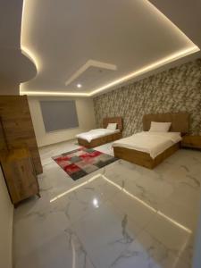 a bedroom with two beds and a tv on the wall at شاليهات لودج in Al Humaizah