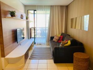 uma sala de estar com um sofá e uma televisão em Marulhos Resort em Porto de Galinhas