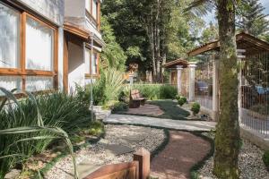 einen Garten mit einer Bank und einem Baum in der Unterkunft LOCAR-IN GRAMADO Residencial Siena Centro in Gramado