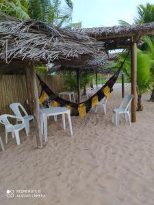 einen Strand mit Stühlen und einer Hängematte im Sand in der Unterkunft Pousada Dolce Mare in Cacha Pregos