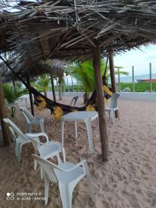 a group of white chairs and tables on the beach at Pousada Dolce Mare in Cacha Pregos