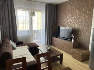 ein Wohnzimmer mit einem Sofa und einem Flachbild-TV in der Unterkunft ApartmanTatryView in Veľká Lomnica