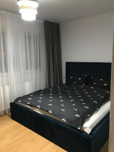uma cama num quarto com uma roupa de cama preta em L&A apartments - Circumvalatiunii em Timisoara