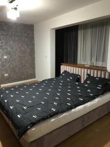 uma cama com um edredão preto com pássaros brancos em L&A apartments - Circumvalatiunii em Timisoara