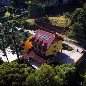 una casa amarilla con techo rojo en un parque en Hotel Vill' Agi, en Campos do Jordão