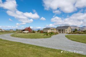 a driveway leading to a house with mountains in the background at Night Sky Cottages - Kea Cottage - LUXURY in Twizel