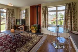 a living room with a glass table and a tv at Night Sky Cottages - Kea Cottage - LUXURY in Twizel