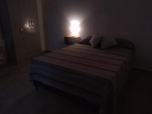Habitación oscura con cama con luz. en Departamento Amoblado en Villa María