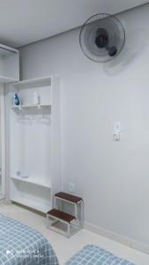a white bedroom with a bed and a fan at Flat familiar com ar,wi fi,cozinha e garagem in Aparecida