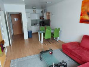 ein Wohnzimmer mit einem roten Sofa, einem Tisch und grünen Stühlen in der Unterkunft Kurpark-Residenz Deidesheim in Deidesheim