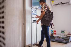 a man standing in front of a refrigerator holding a cell phone at Varanasi Hotel Boutique Aeropuerto in Cartagena de Indias