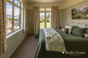 a bedroom with a bed and a large window at Night Sky Cottage - Kahu Cottage - HOT TUB in Twizel