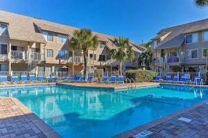 a swimming pool with blue chairs and condos at Hilton Head Villa with Balcony Walk to the Beach! in Hilton Head Island