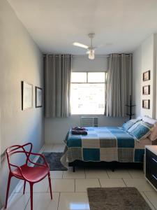 a bedroom with a bed and a red chair at Copa apt°/ 1Qd da Praia bela vista in Rio de Janeiro