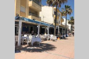 un restaurante con mesas y sillas blancas y palmeras en Villa Matilde Modern 2 Bedroom Apartment Close to Beach, en San Luis de Sabinillas